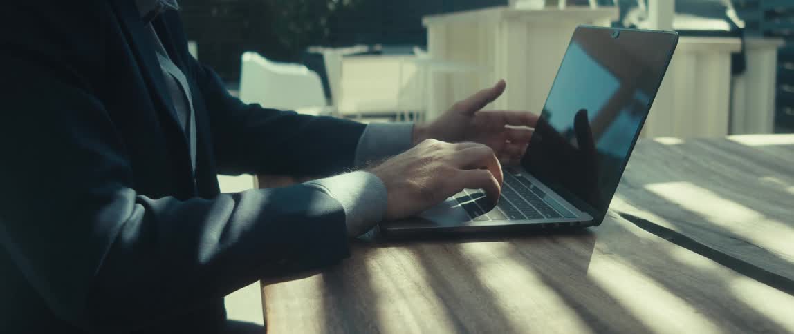 Man in suit sitting typing on a laptop