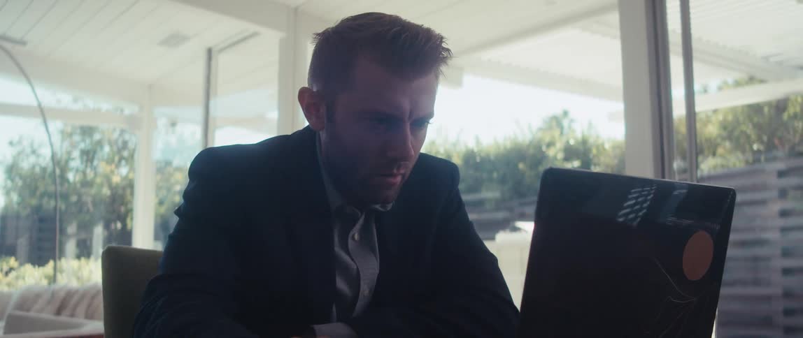 Man in blazer sitting focused in front of laptop