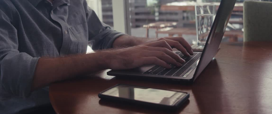 Hands of a person typing on a laptop on the table