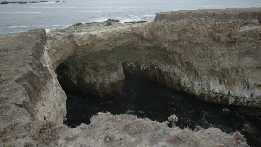 A large opening in between some rocks that is filled with water