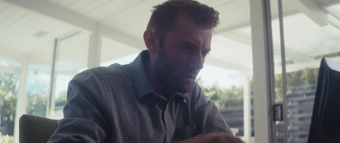 A man working on a laptop and checking his smart phone