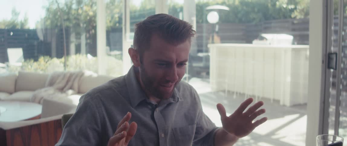 Ecstatic man opening his palms while sitting in front of a laptop