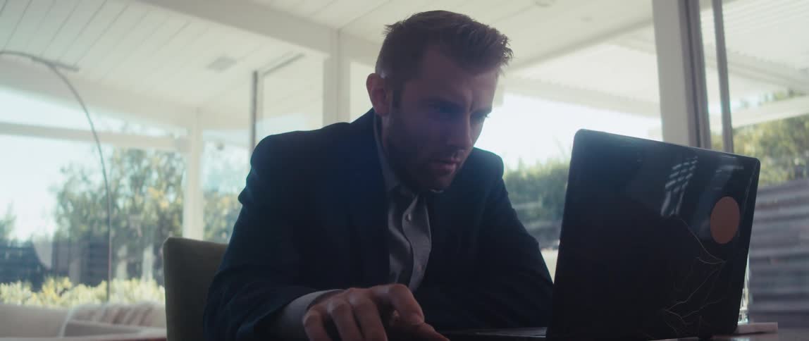 Man sitting at living room table working on laptop