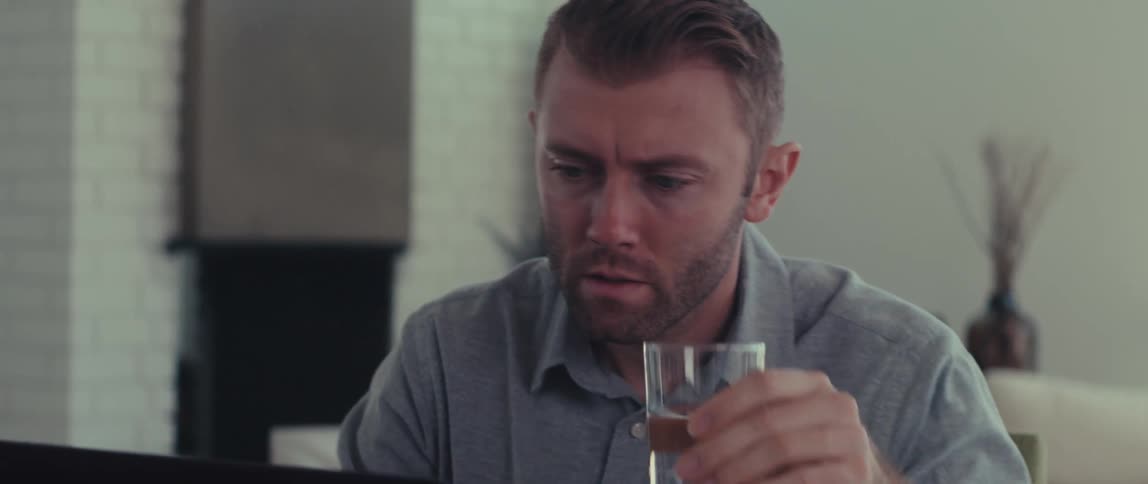 Man sitting with a glass of water and an open laptop in front of him