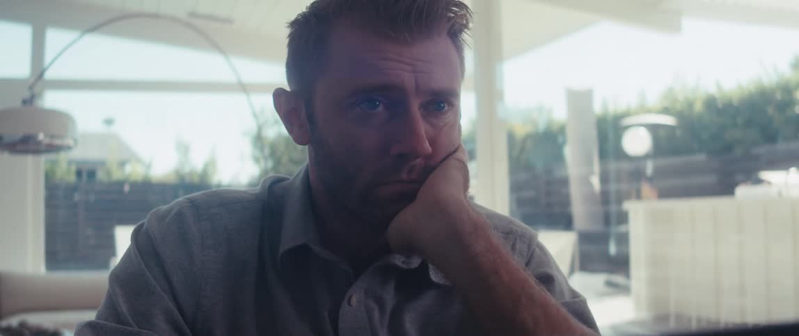 A man in a shirt works on a laptop in a welllit living room in a modern home