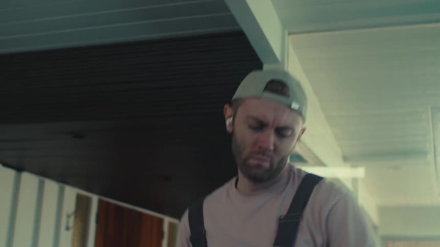 A man is listening to music and dancing while vacuuming