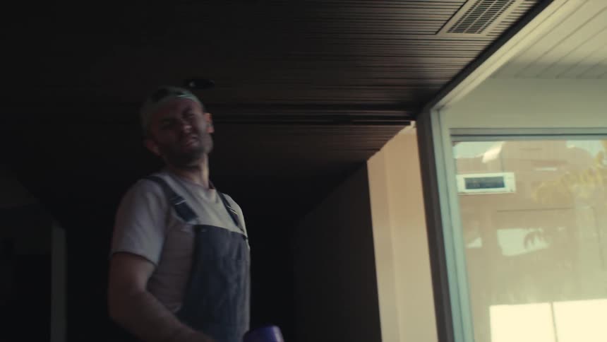 A man singing and dancing to music on his earbuds while vaccuming