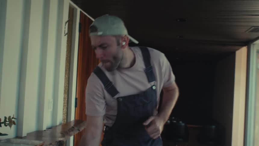 A man is dancing and listening to music as he cleans