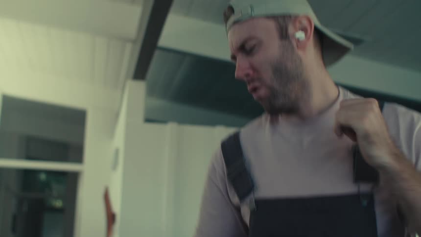 A janitor dances to music in his earbuds while cleaning an office