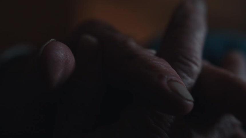 An elderly man crosses his hands