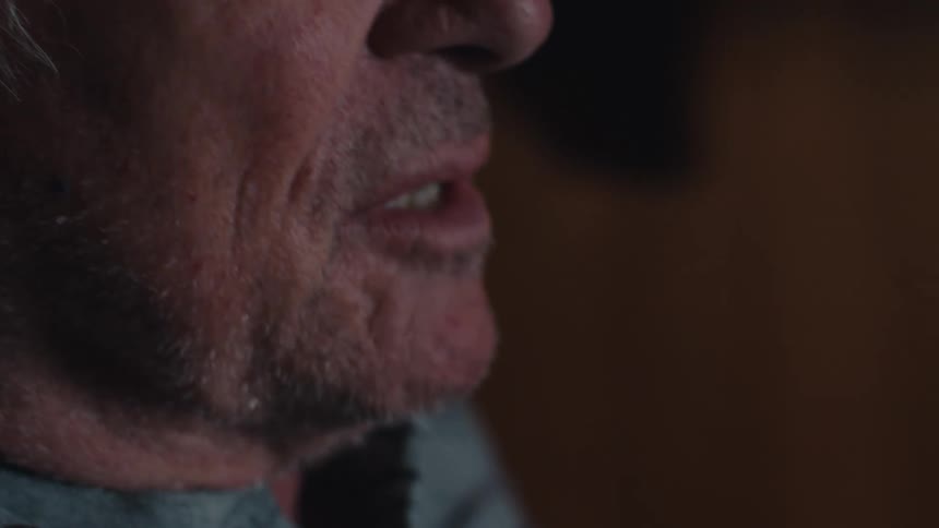 Close up of the face of an elderly man watching tv at night