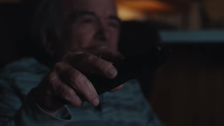 A man is changing channels on the television with a remote