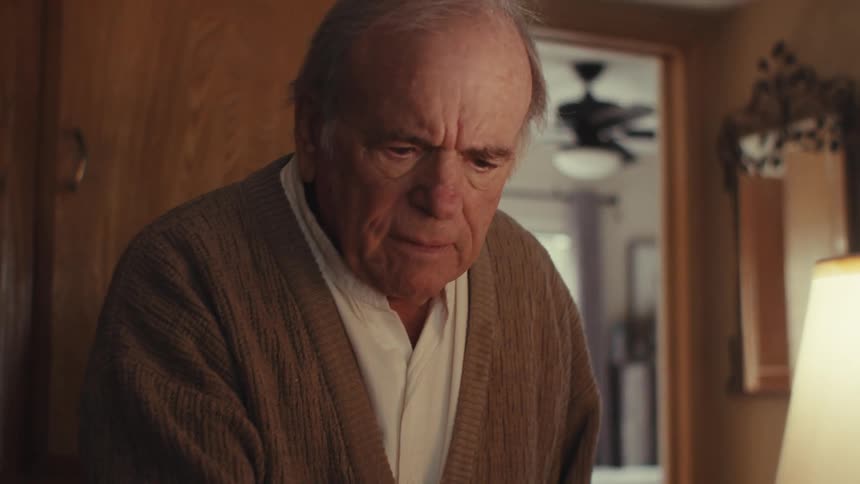 Elderly man standing up and answering a phone call