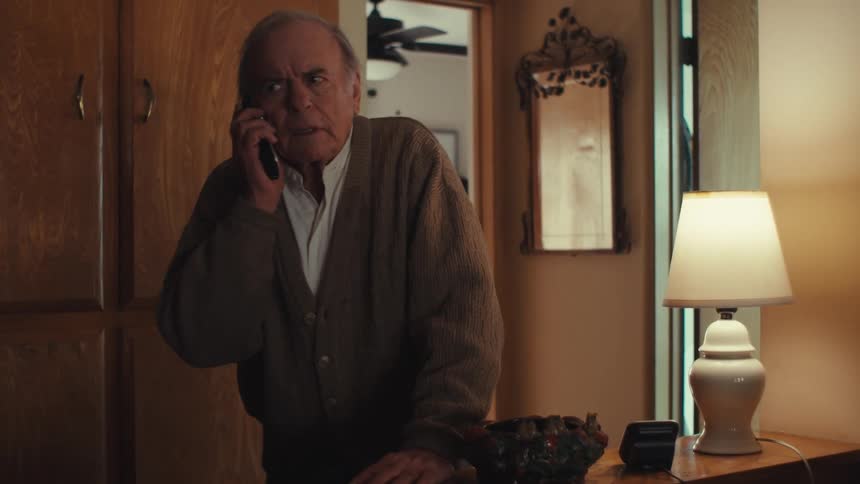 Elderly man standing up going to another room and answering the phone