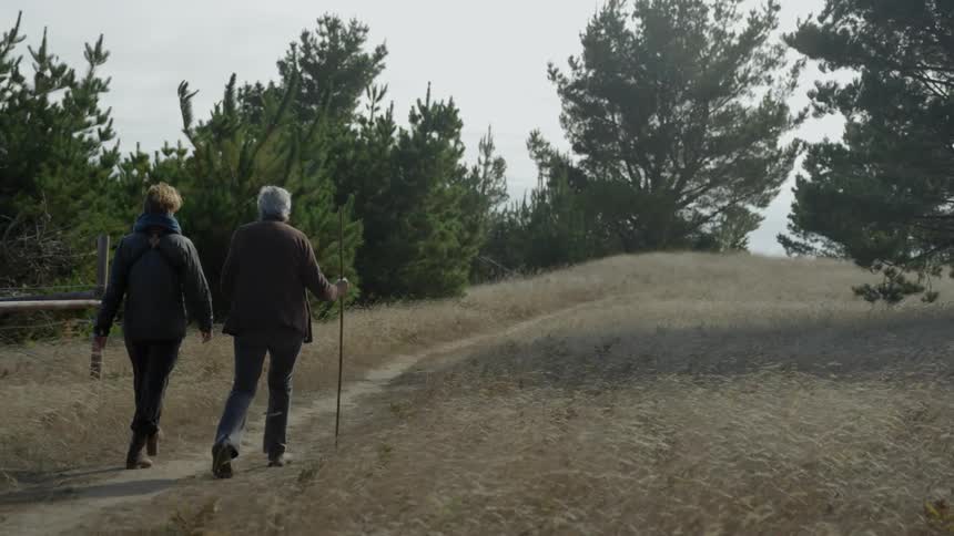 Two people hike a trail in a field