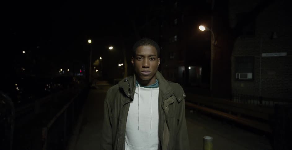 A man stands on a city street at night