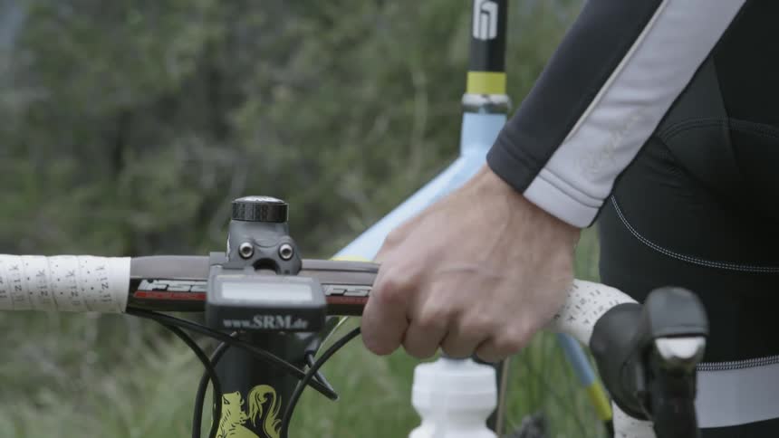 A man lifts and moves his racing bicycle