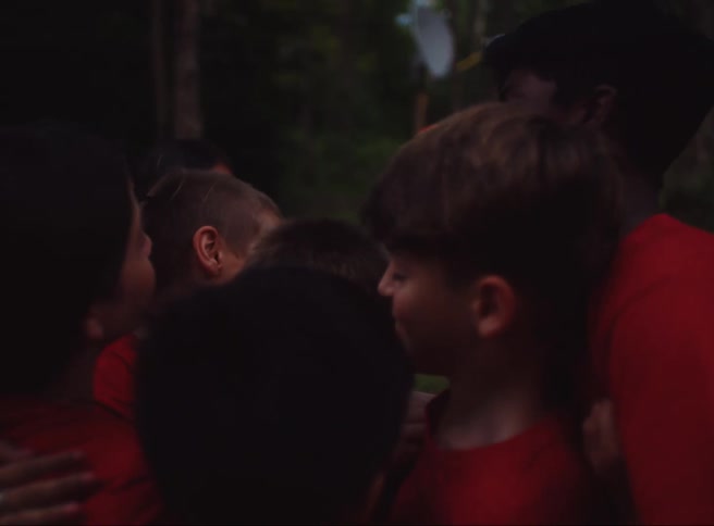 Friends smile during a group hug in a field near the woods