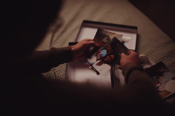 Man sitting on his bed looks through photographs