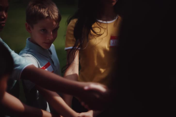 Several youths form a link of interconnected hands during a group activity