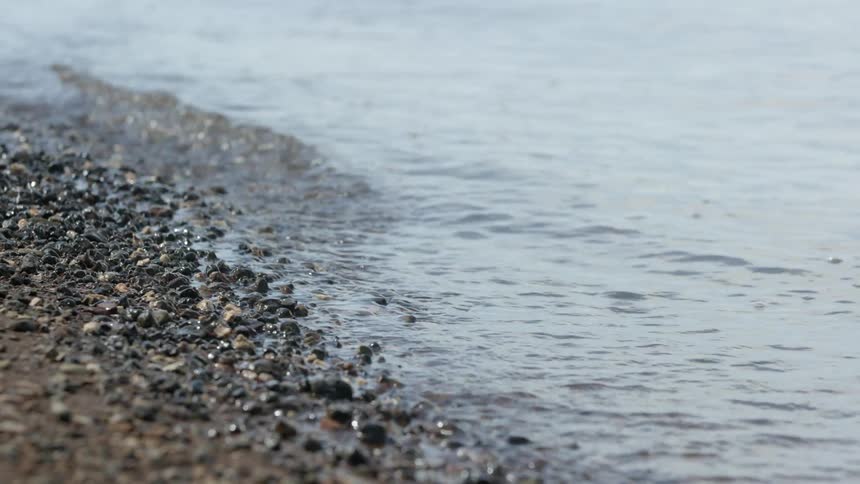 Water flows onto a pebbly beach