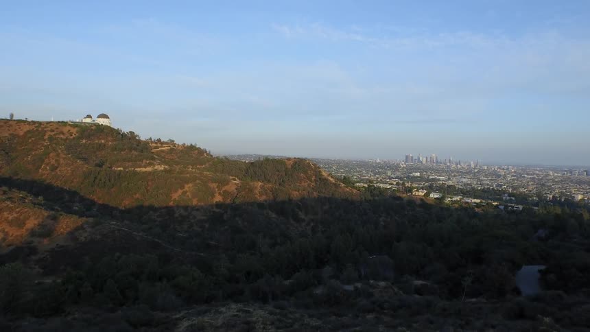 A view of a large mountain with a house on top and a city far below