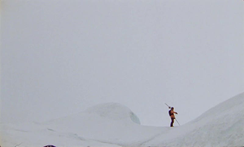 Person with ski equipment in the middle of a snowy mountain on a foggy day