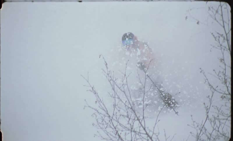 Person skiing down a mountain with snow obscuring them as they go