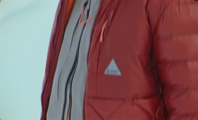 A man stands outside in the snow dressed in multiple layers of clothing