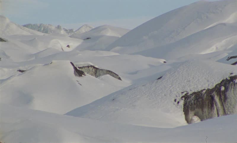 A mountainous region with a lot of snow on the ground and some rocks that are partially showing