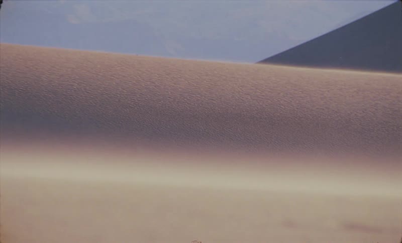 Sand blows around on a large dune in a desert