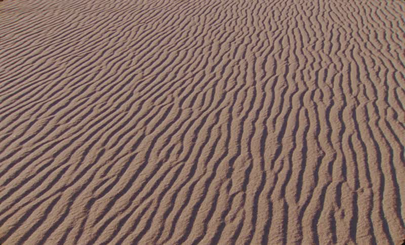 Intricate wavy patterns etched into the sand create a textured desert landscape