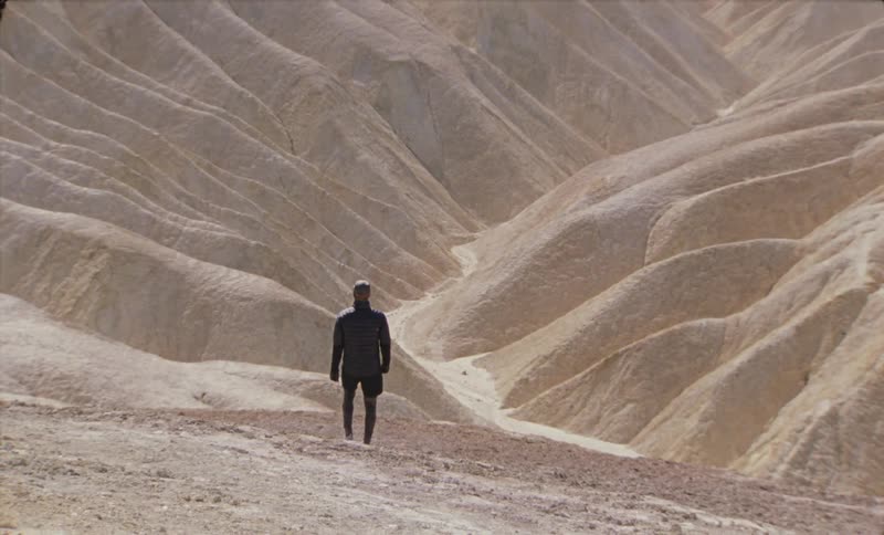 A lone individual walking through a rugged mountain landscape