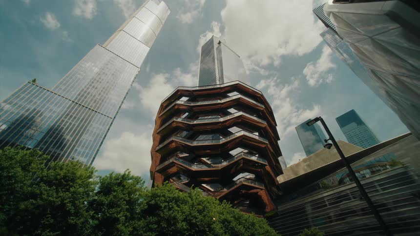 The facade of a huge commercial building surrounded by other buildings with the exterior full of glass windows