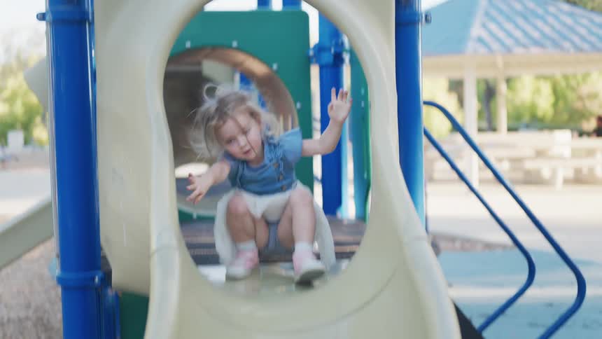 Little blonde girl playing on a playground in an open air area