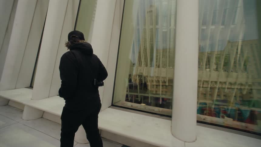 Man with a camera walking next to a building with modern architecture