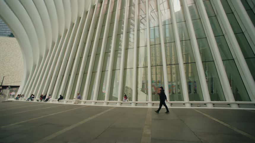 Man walking down sidewalk in front of a large building