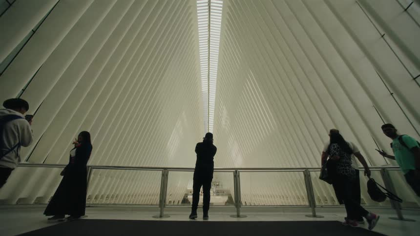 Some of the people looking at a large architectural space from a balcony shoot video