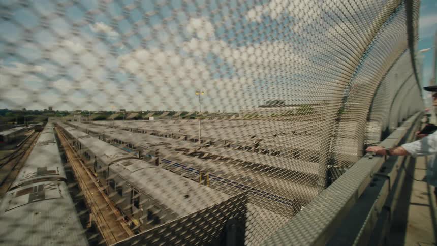Man takes a photo of a train yard with many parked trains behind a chainlink fence