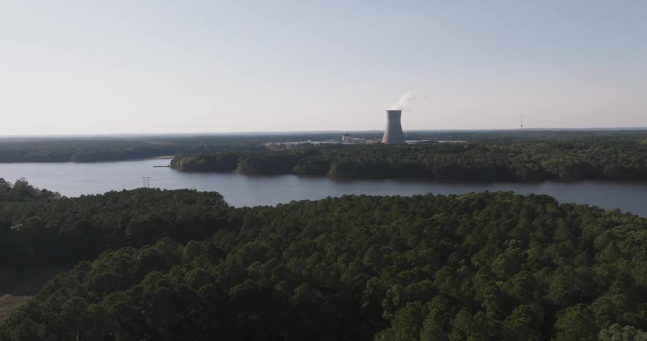 Aerial view of a chimney emitting pollutants in an environment surrounded by a river and forest