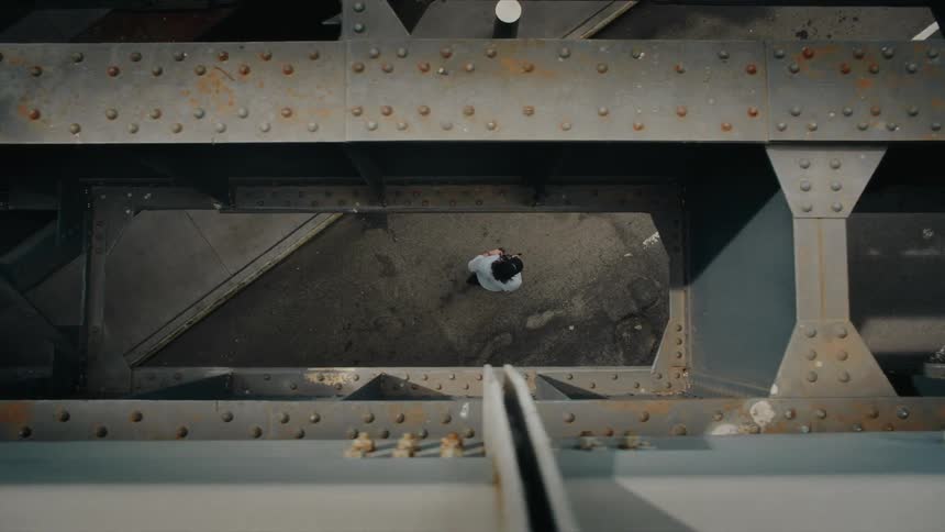 Overhead view of a photographer using a professional camera as he walks through the city below an overpass