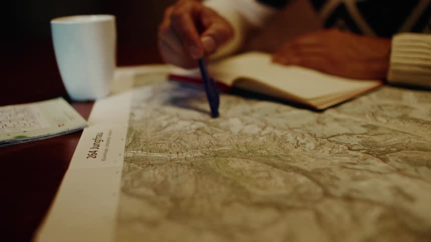 Two people with their hands interacting on a map on a table