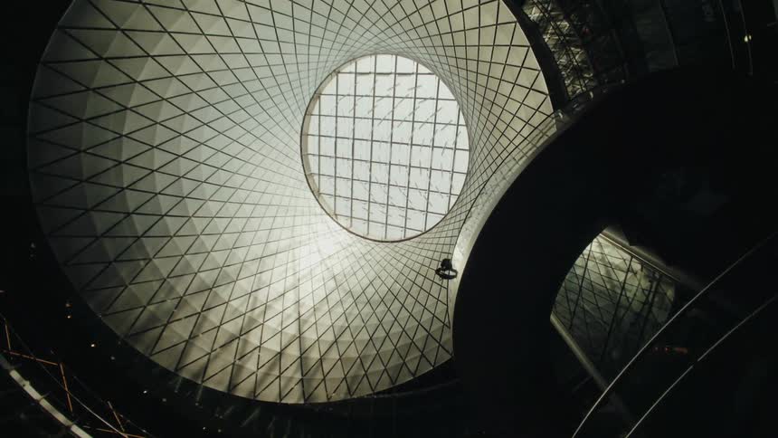 The interior of a building with a circular roof and lit by natural light
