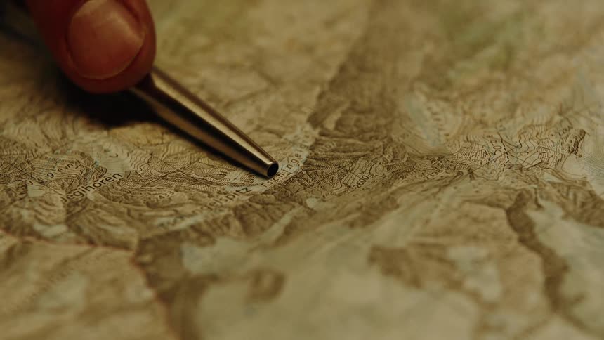 Finger holding a pen and on top of a map