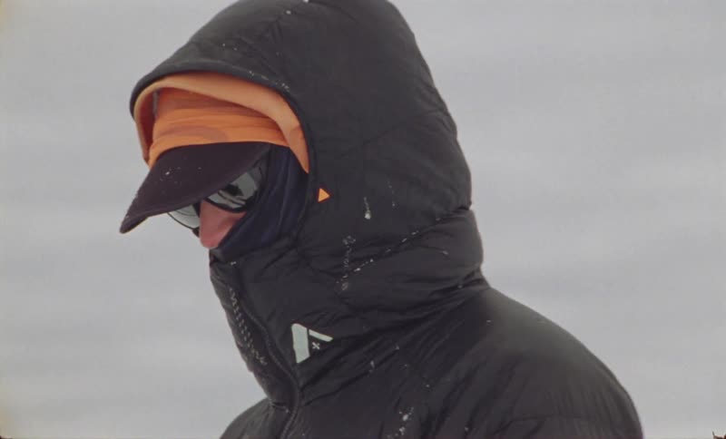 Person with winter jacket and sunglasses on a snowy mountain