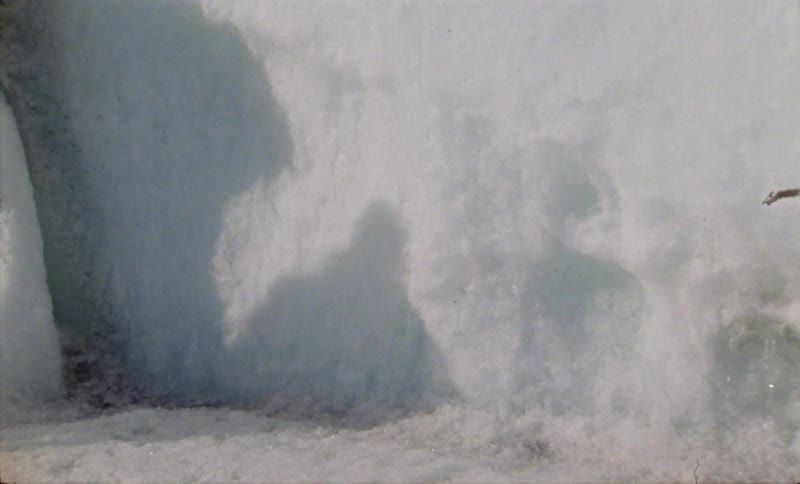 A person moving through the snow casts a shadow on a snow covered surface