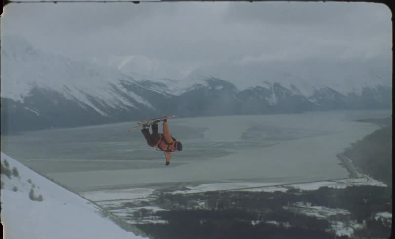 Person skiing on a snowy mountain and jumping in an aerial maneuver
