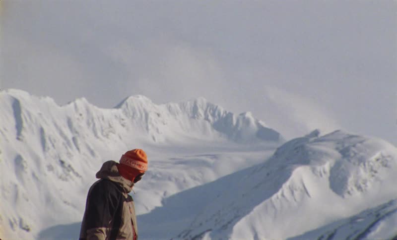 Person wearing a hat and winter clothes is on a snowy mountain