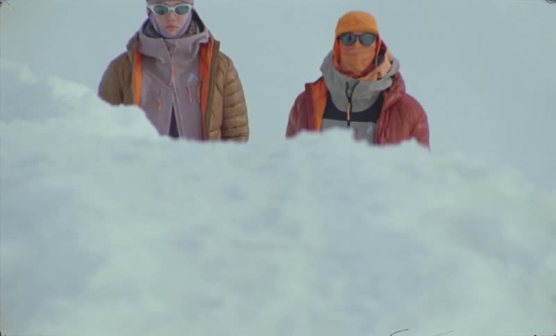 Two people in winter clothes have their faces covered and in front there is a lot of white snow