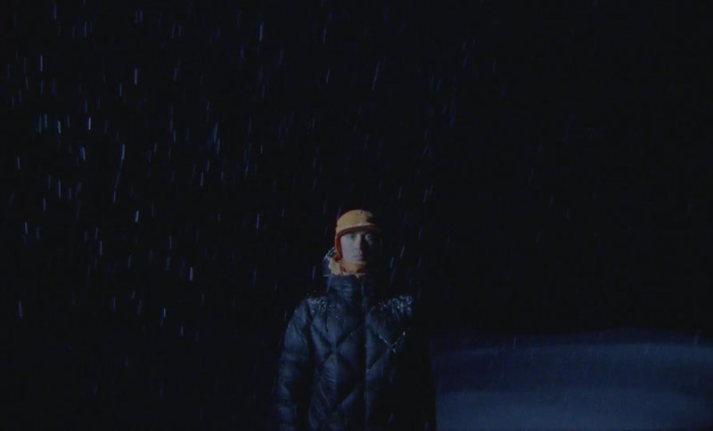 Man in winter jacket and hat in natural environment at night with snow